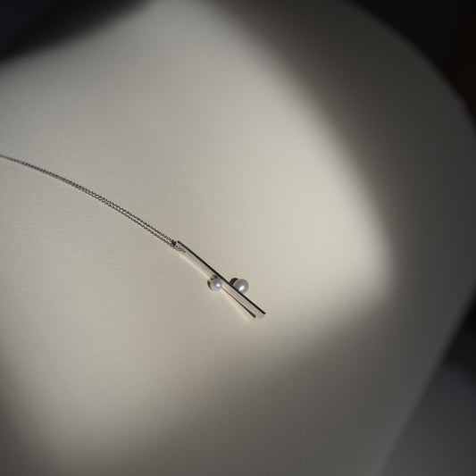 Side View of Linear Necklace: A side profile of the Linear Necklace, showing the precise lines and modern aesthetic of the design.