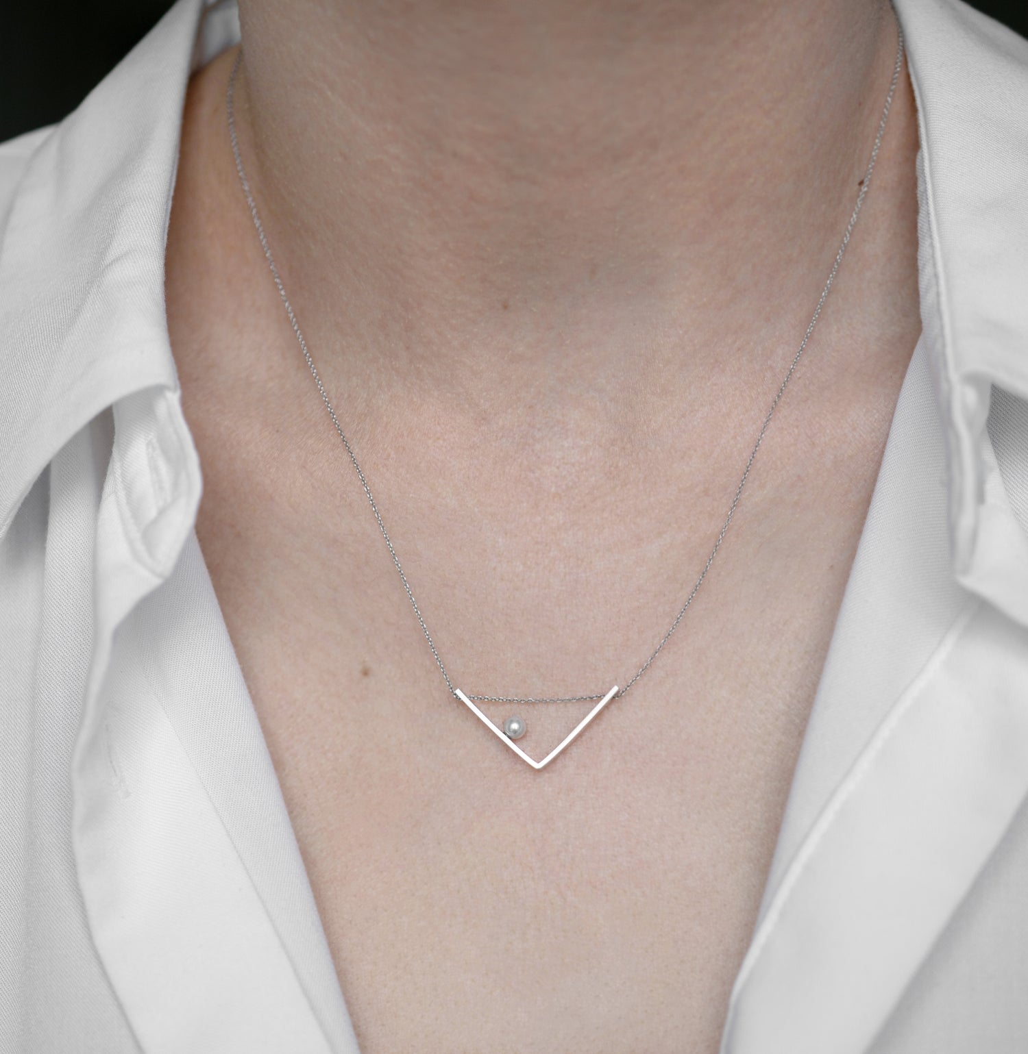 A woman showcasing the elegant Angle necklace, demonstrating its minimalist sophistication and perfect fit for everyday wear.